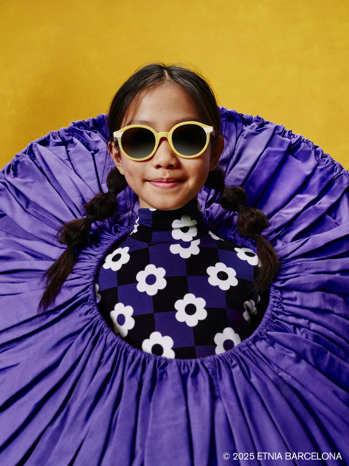 Girl in yellow round Etnia Barcelona kids' glasses, available at Boardwalk Eye Care in Cambridge, Ontario