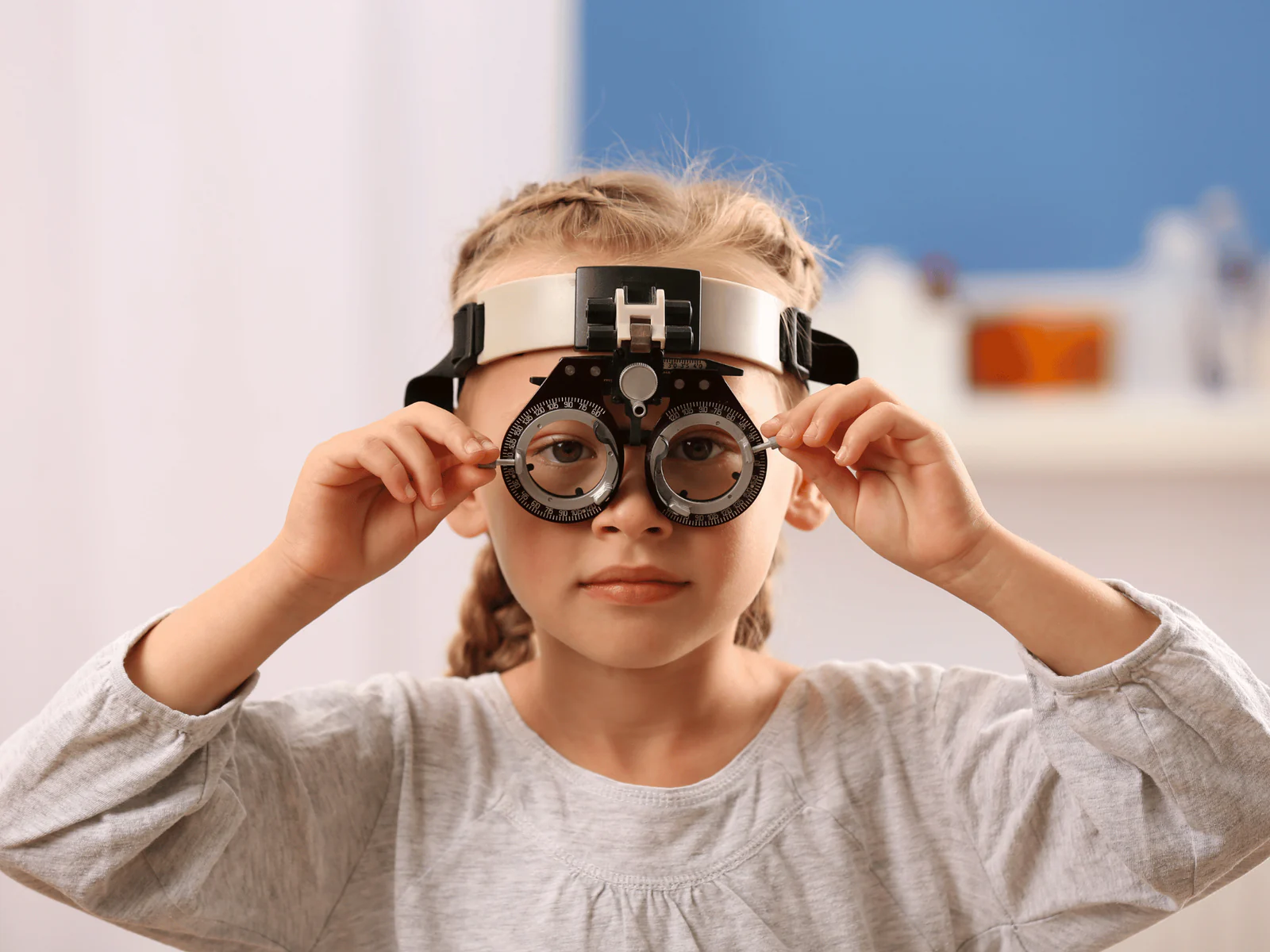 Child looking through a phoropter during a pediatric eye exam